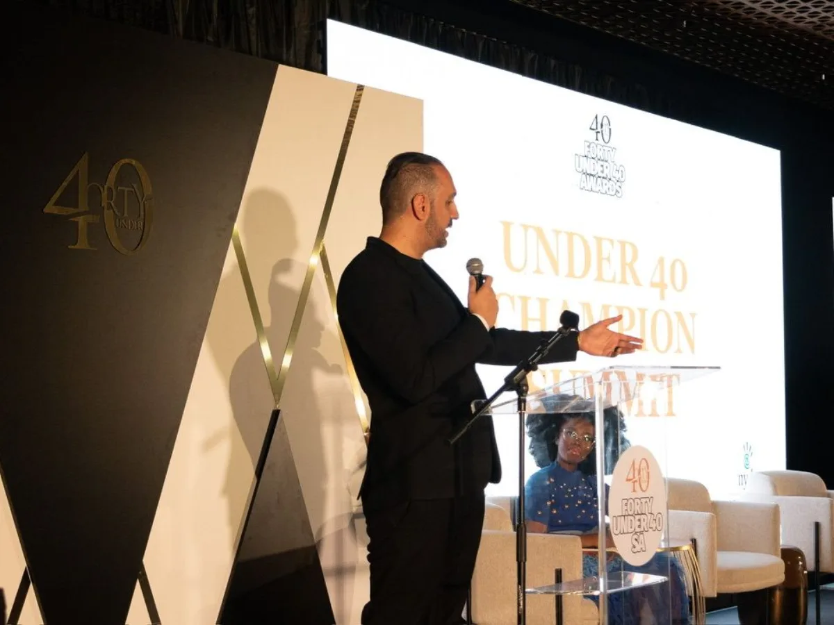 Arash Rezaei speaking on stage with a microphone at a summit.