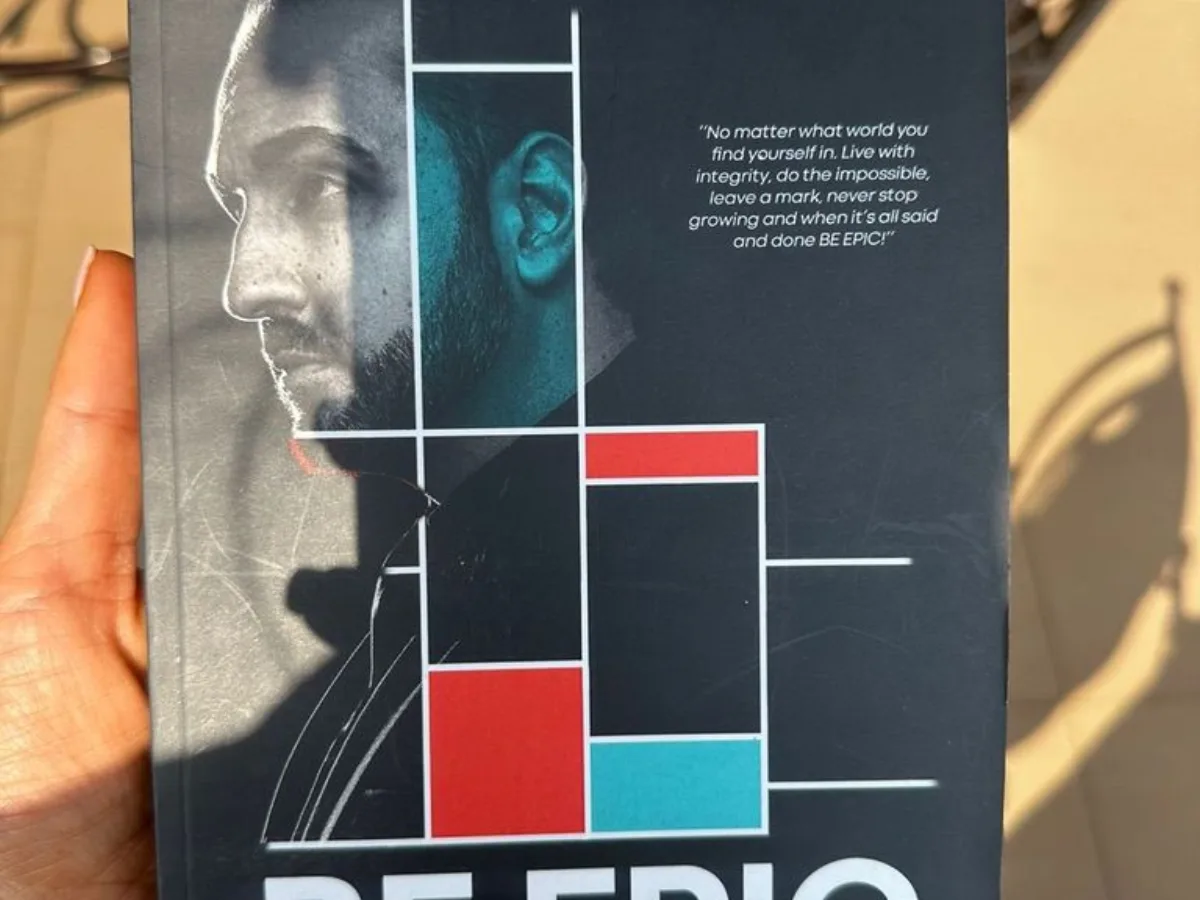 A hand holding Arash Rezaei's book, Be Epic.